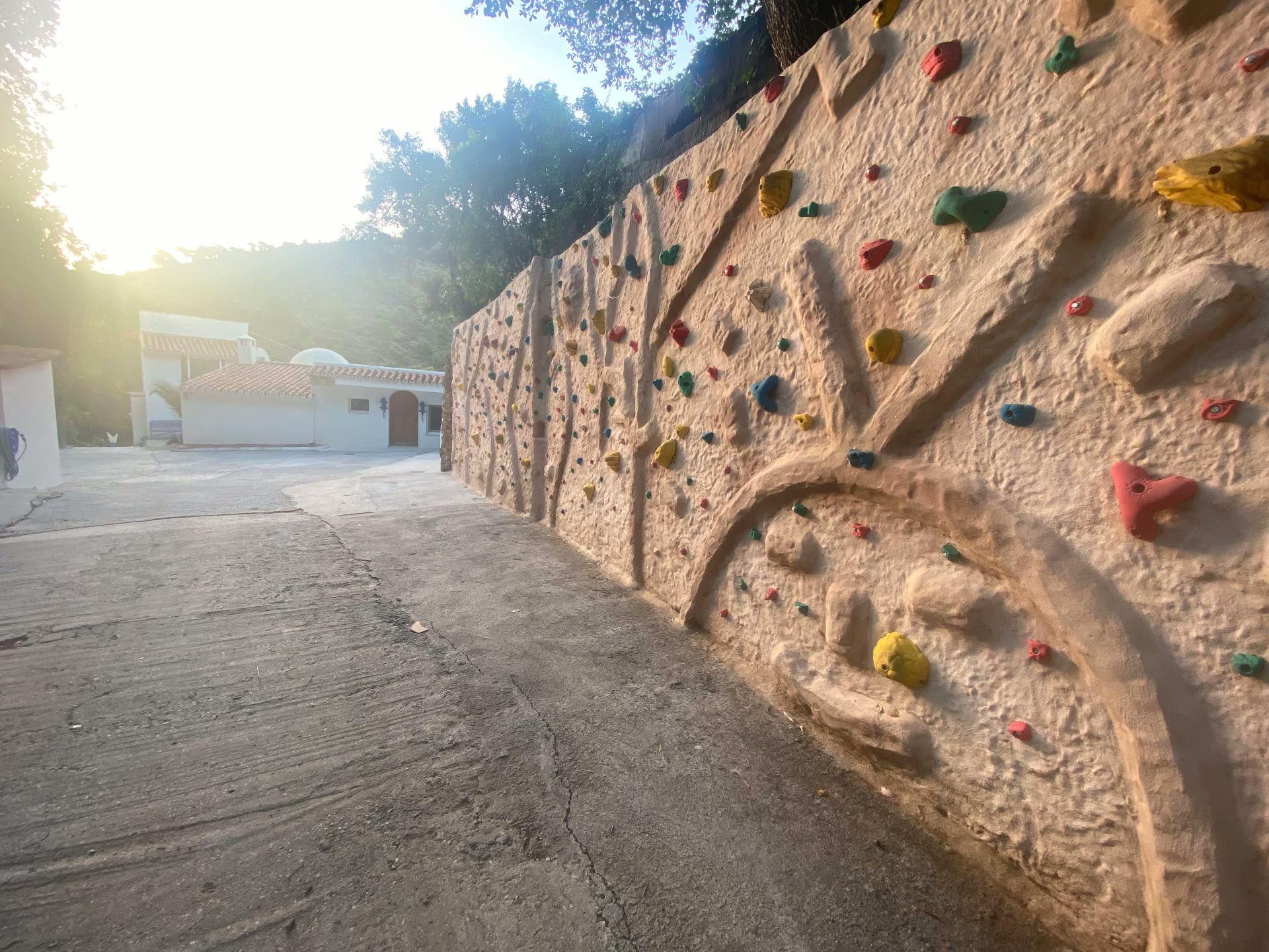 The Academy's outdoor climbing wall with coloured holds at sunset